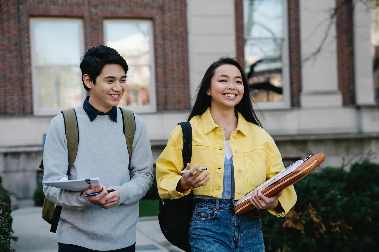 two students talking while holding their materials