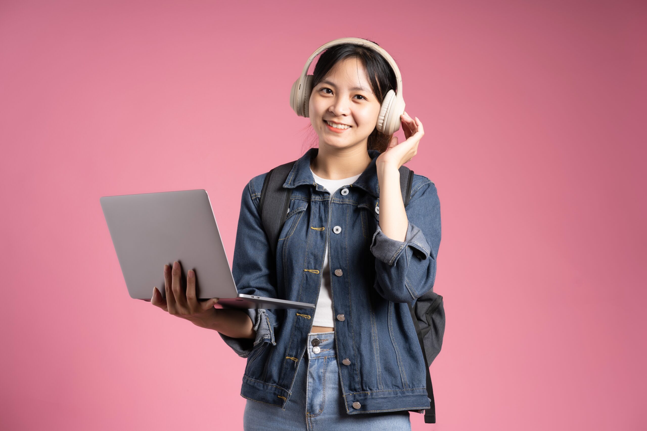 an ABM student wearing headphones and holding a laptop