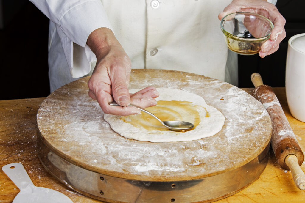 a chef putting in olive oil on a dough