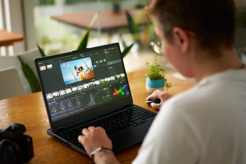 Professional video editor adjusting colors on laptop in bright office.